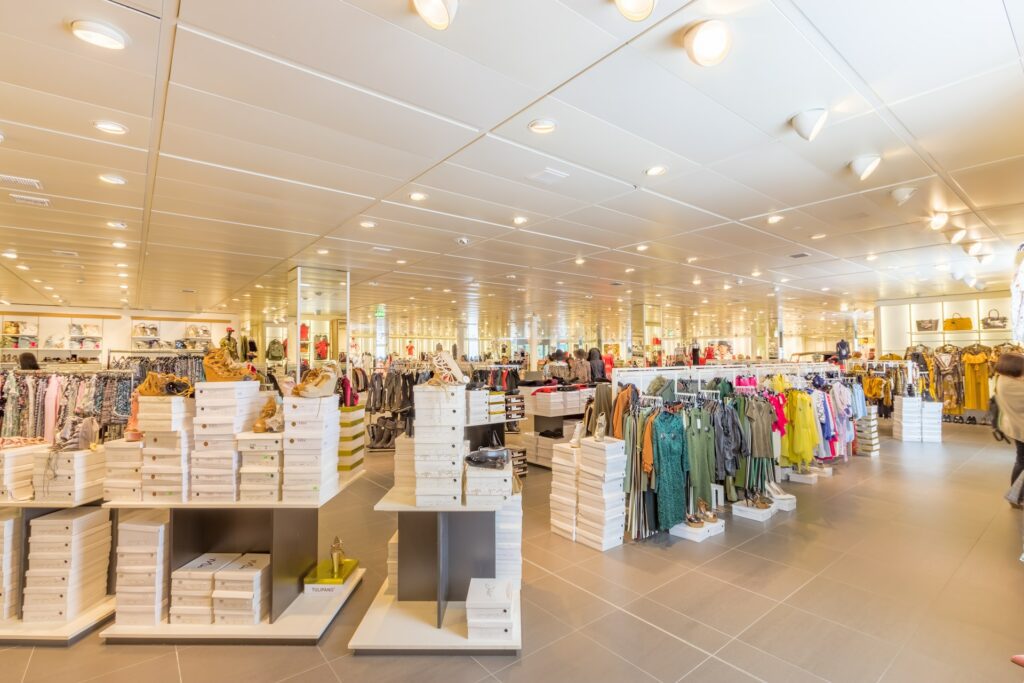 A spacious retail store with neatly arranged racks of clothes, stacks of shoeboxes, and bright overhead lighting to boost appeal.
