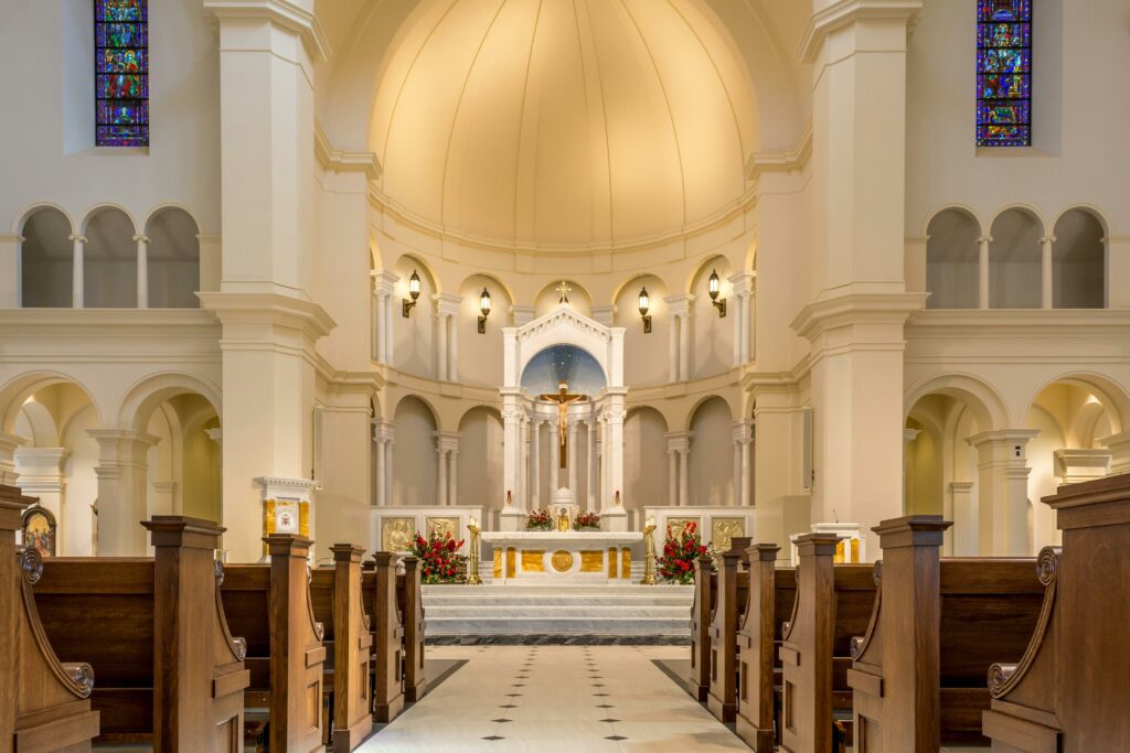 Interior of a church with wooden pews, a central aisle leading to an ornate altar, and stained glass windows, all meticulously kept through regular church maintenance.